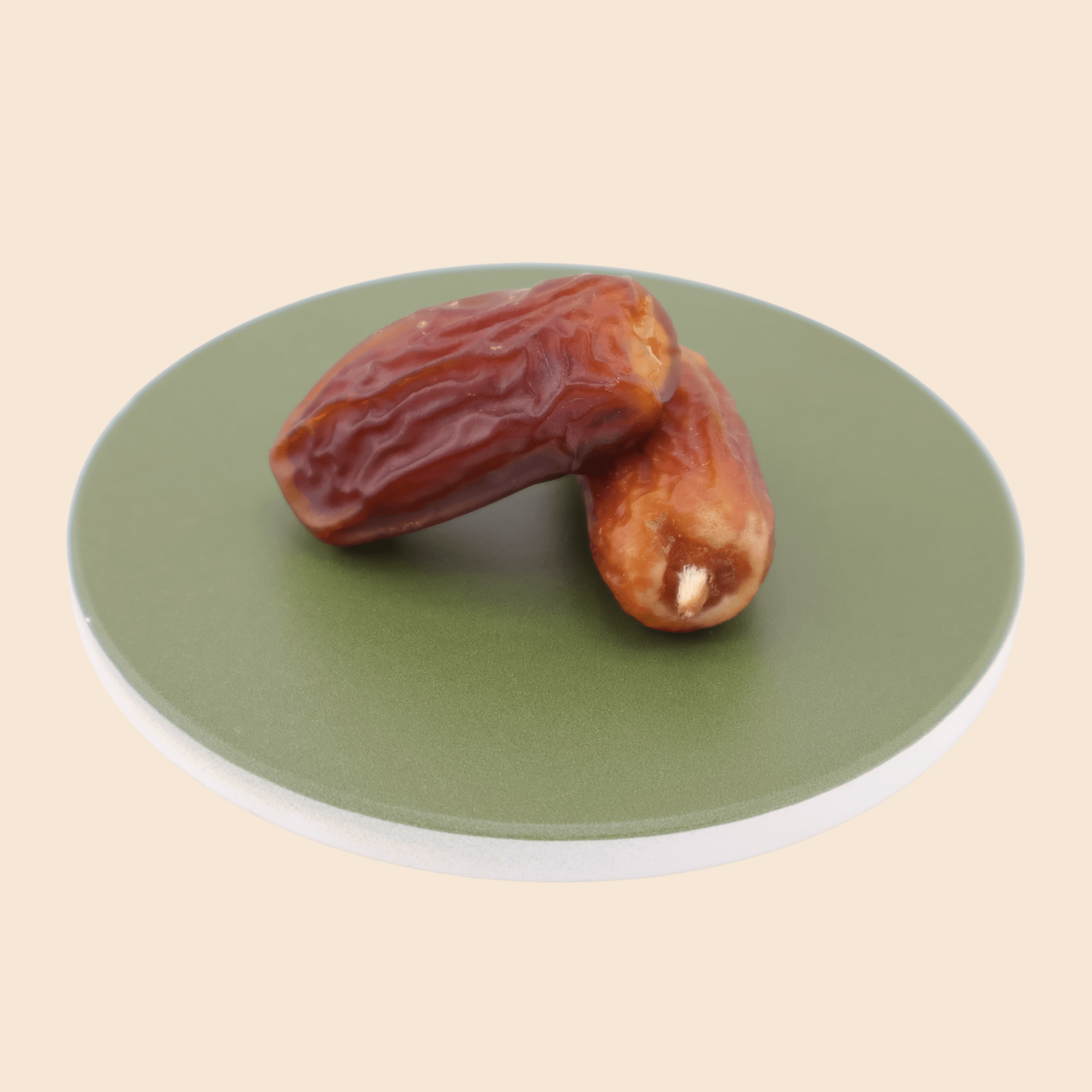 Two Mabroom dates from Mighty Mejdool placed on a green plate, showing their rich reddish-brown colour and chewy texture.
