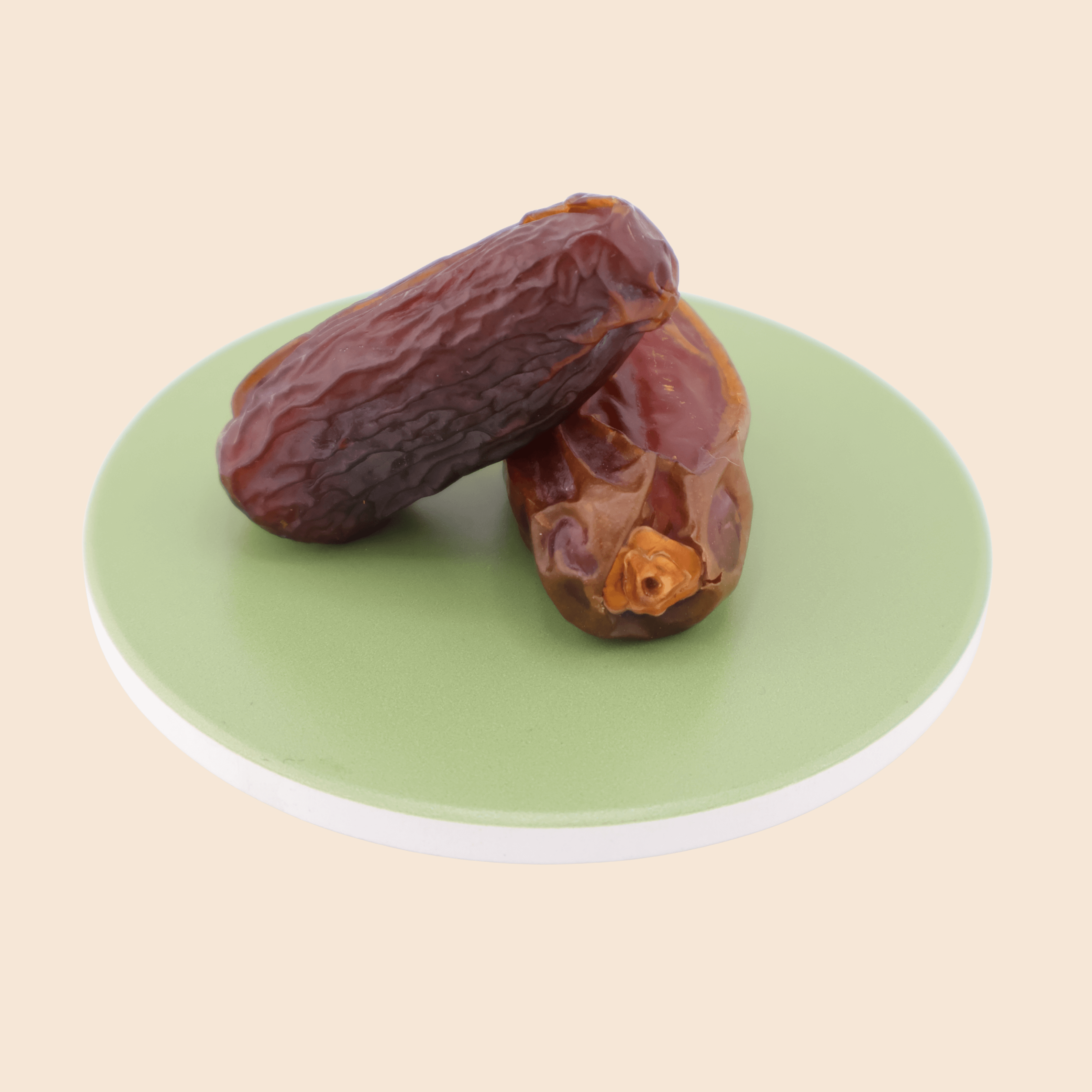 Two large Medjool dates from Mighty Mejdool on a green plate, showing deep amber colour and chewy caramel texture.