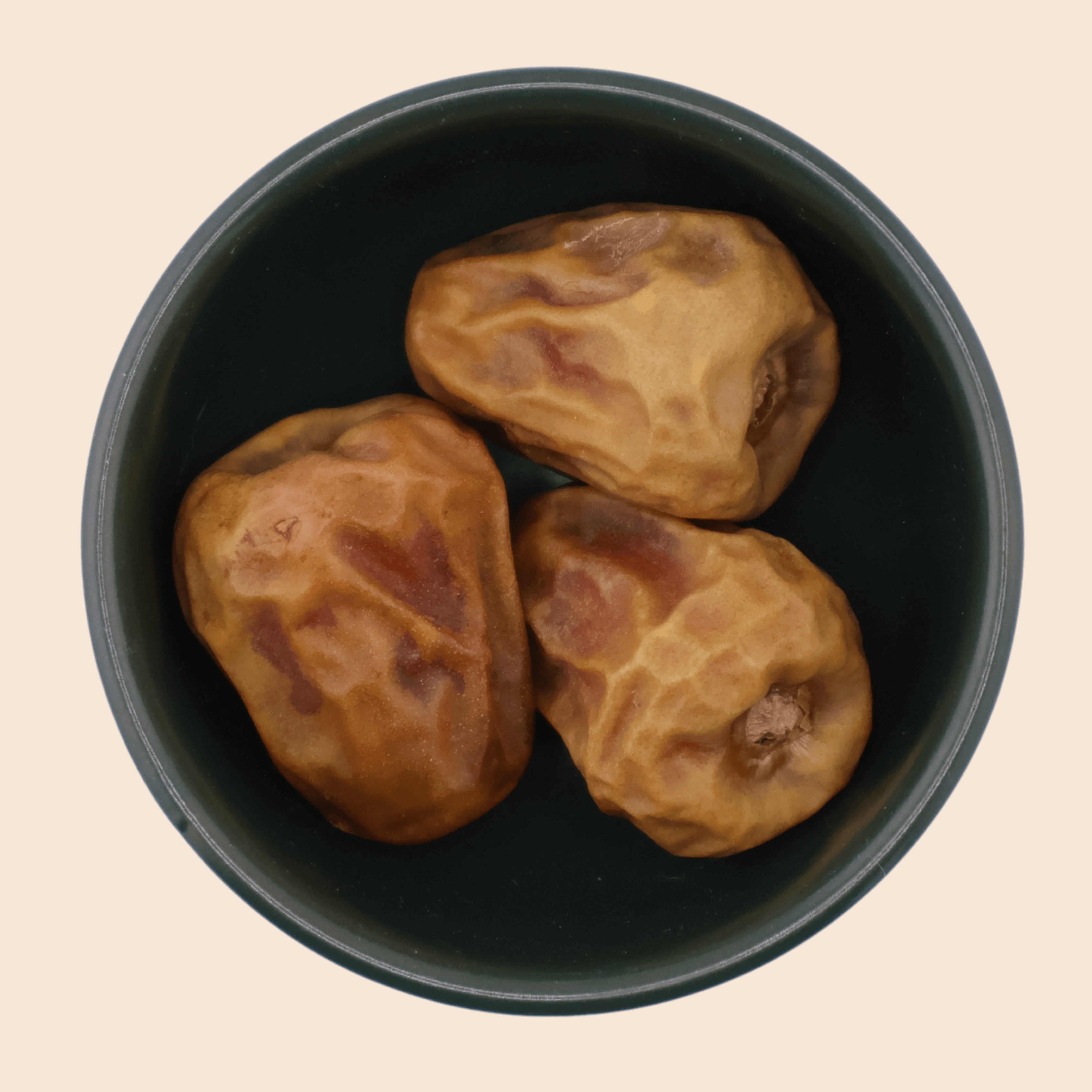 Three Sukkari Gaf dates from Mighty Mejdool in a dark green bowl, showing golden-brown colour and crisp, toffee-like sweetness.