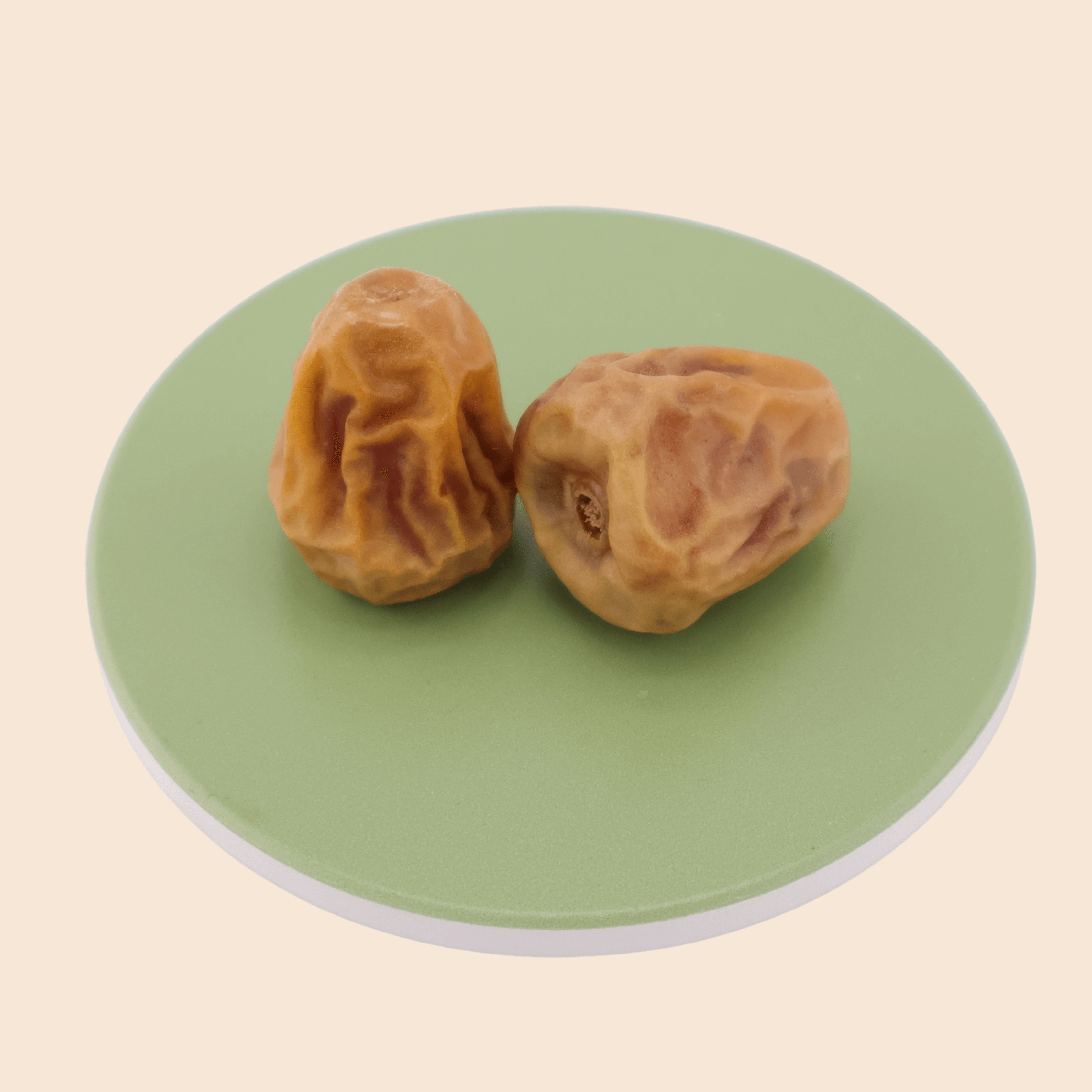 Two Sukkari Gaf dates from Mighty Mejdool on a light green plate, showing golden-brown colour, firm texture, and toffee-like sweetness.