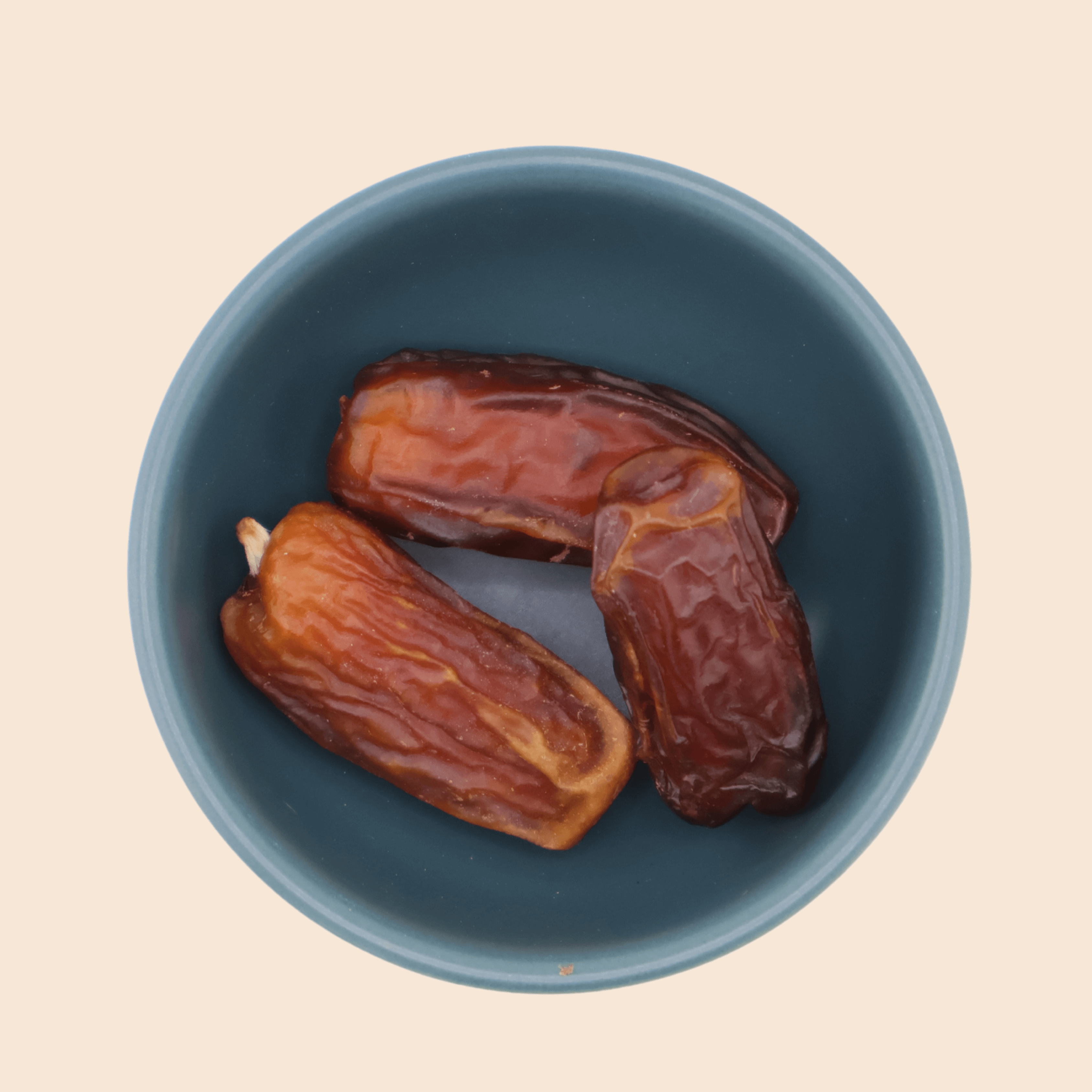 Three premium Mabroom dates from Mighty Mejdool in a blue bowl, showcasing their rich reddish-brown colour and chewy texture.