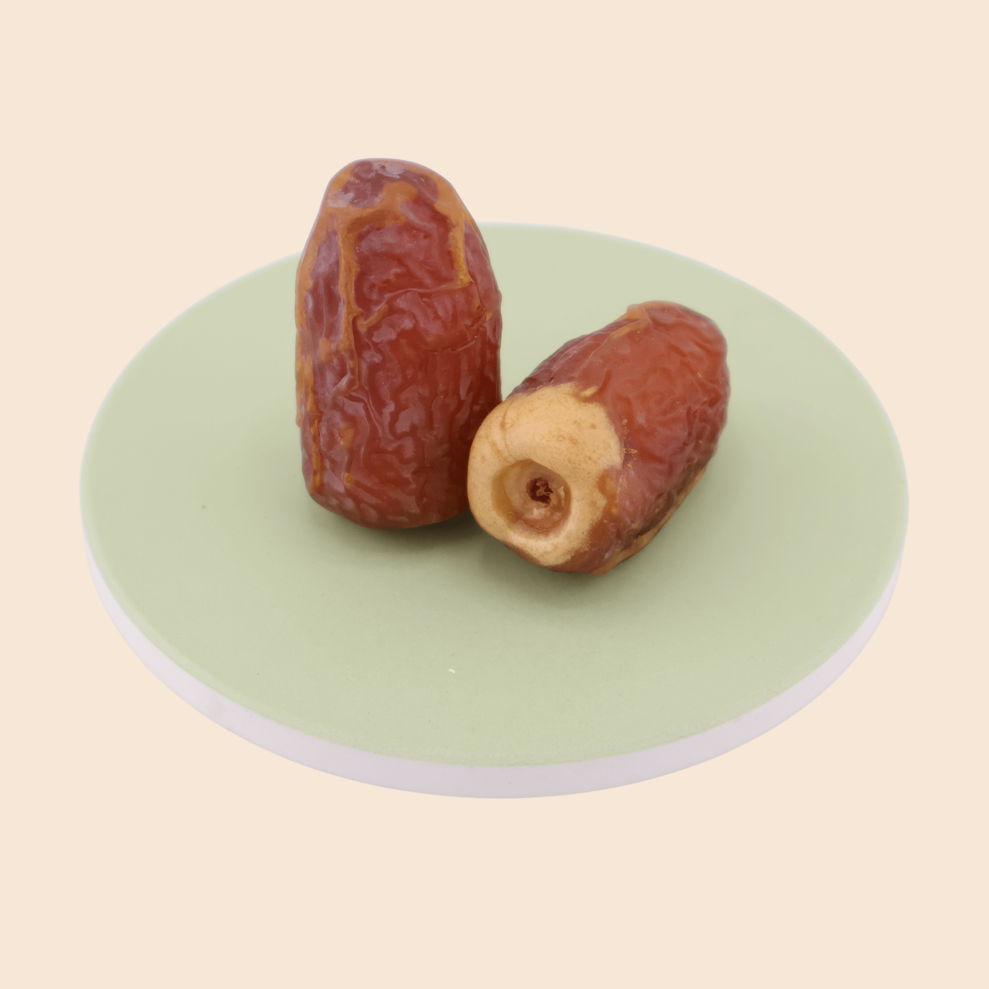 Two Sagai dates from Mighty Mejdool on a light green plate, showing their golden-brown two-tone colour and chewy texture.