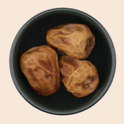 Three Sukkari Gaf dates from Mighty Mejdool in a dark green bowl, showing golden-brown colour and crisp, toffee-like sweetness.